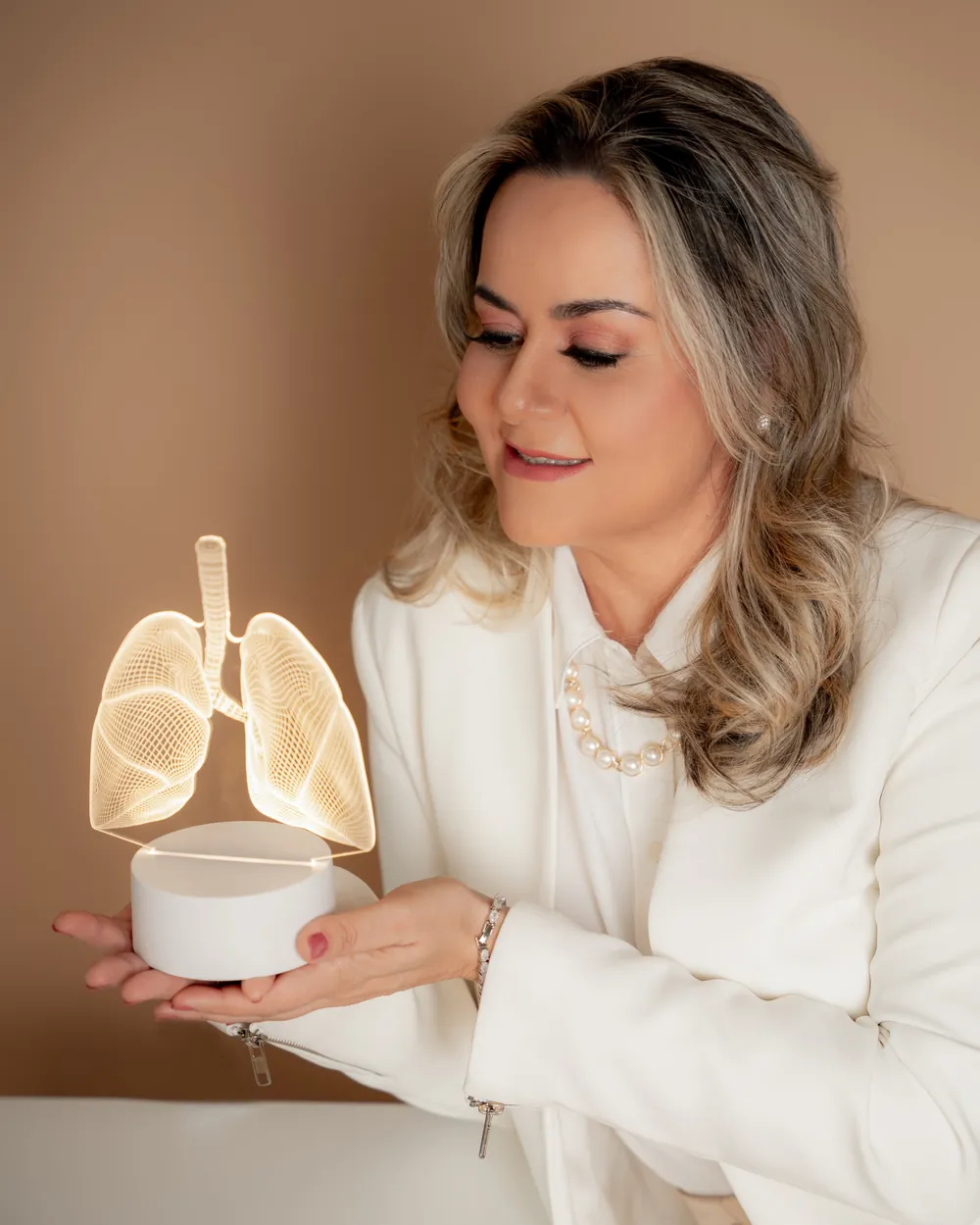 Dra. Kamilla Tonini segurando uma luminária em forma de pulmão